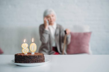 seçici odak masada evde kanepe ve Doğum günü pastası Smartphone'da konuşurken kamışı ile üst düzey kadın