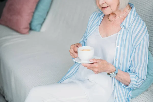 Частичный Вид Пожилой Женщины Чашкой Ароматного Кофе Сидящей Диване Дома — Бесплатное стоковое фото