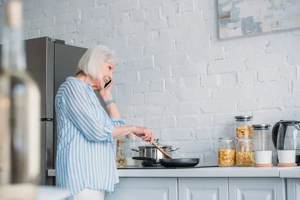 Side View Smiling Senior Woman Talking Smartphone While Cooking Dinner — Stock Photo, Image