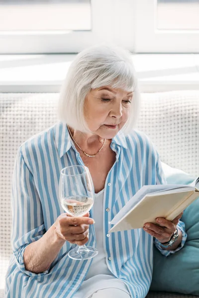 Retrato Mujer Mayor Enfocada Con Copa Vino Libro Lectura Sofá — Foto de Stock