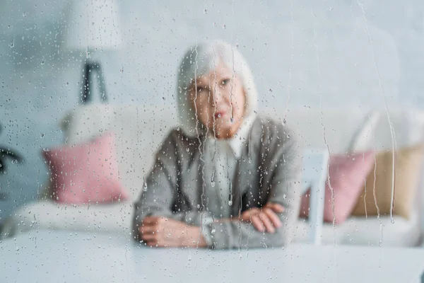 Избирательный Фокус Заботливой Пожилой Женщины Трикотажной Куртке Сидящей Столом Одиночестве — Бесплатное стоковое фото