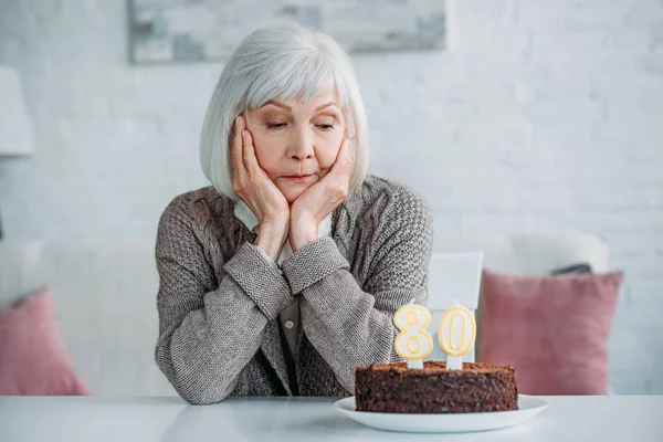 Senhora Sênior Pensativo Sentado Mesa Com Bolo Aniversário Com Velas — Fotografia de Stock