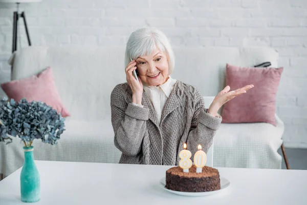 Портрет Счастливой Пожилой Женщины Разговаривающей Смартфоне Сидя Столом Праздничным Тортом — стоковое фото