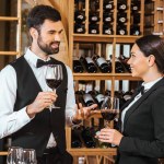 Pareja de administradores de vino haciendo degustación juntos y charlando en la tienda de vinos
