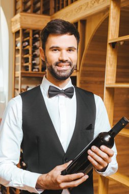 Lüks şarap şarap mağazasında şişe şarap steward genç gülümseyen