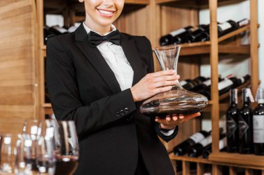kırpılmış gülümseyen kadın şarap steward sürahi şarap mağazasında elinde kadeh