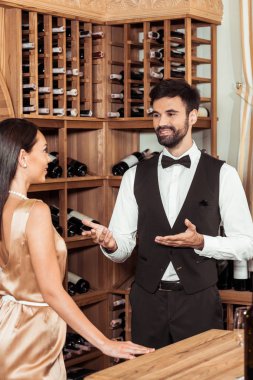 wine steward chatting with beautiful female customer at wine store clipart