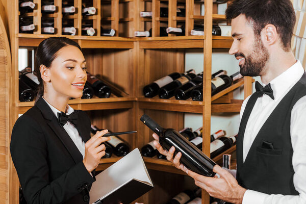 couple of young wine stewards doing stocktaking of wine