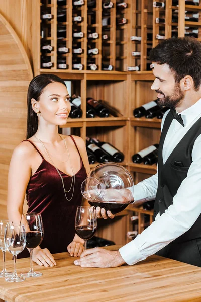 wine steward pouring wine for client from decanter at wine store