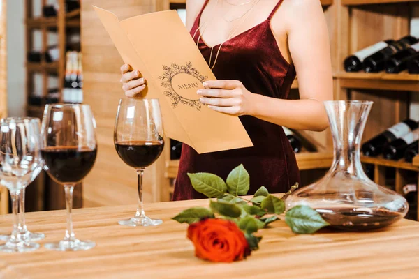 Cropped shot of woman in red dress reading menu card at wine store — Stock Image Cropped Shot Woman Red Dress Reading Menu Card Wine Store Royalty Free Stock Images