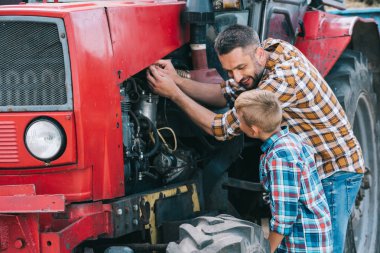 happy father and son repairing tractor engine together clipart