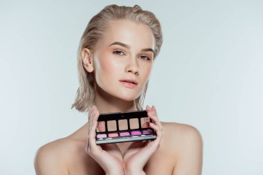 blonde girl holding palette with eyeshadows, isolated on grey clipart