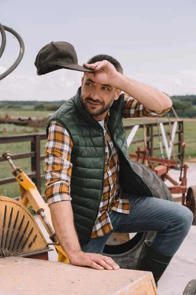 英俊的男性农夫拿着帽子 看着一边在牧场工作 — 图库照片