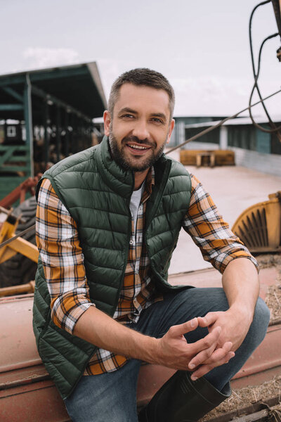 handsome male farmer sitting and smiling at camera at ranch