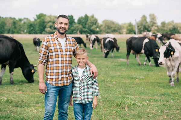 Padre Hijo Sonriendo Cámara Mientras Están Pie Cerca Ganado Pastando —  Fotos de Stock