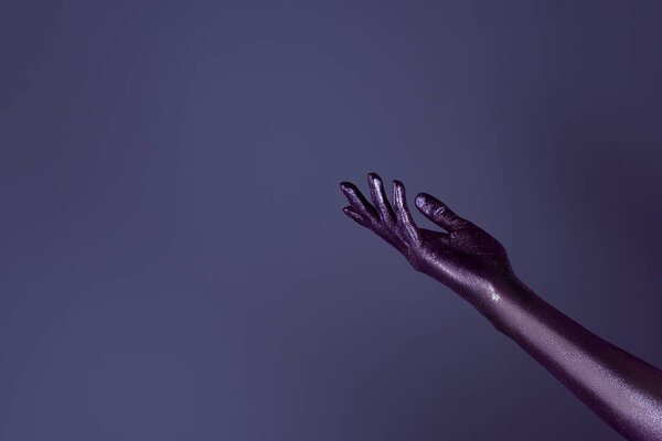 cropped view of female hand in ultra violet glitter, isolated on purple
