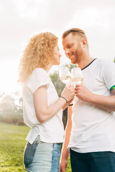 Vista Lateral Feliz Pareja Joven Sosteniendo Vasos Vino Sonriéndose Parque — Foto de Stock