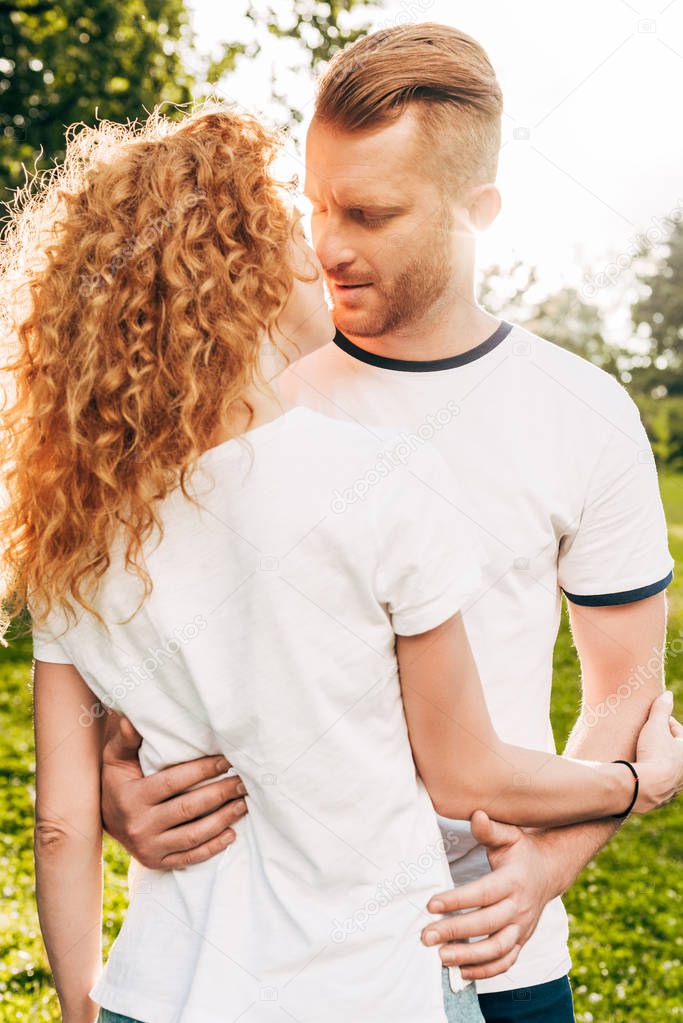 beautiful redhead couple able to kiss while embracing at park