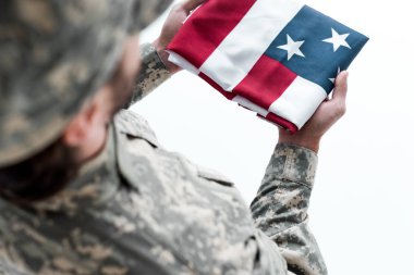 partial view of male soldier in military uniform with american flag in hands clipart
