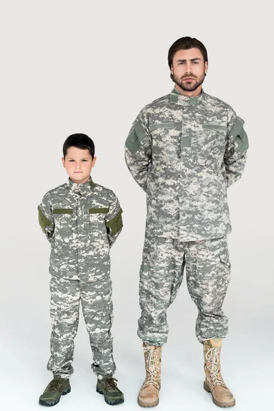 父亲和儿子在军事制服看照相机在灰色背景 — 免费的图库照片