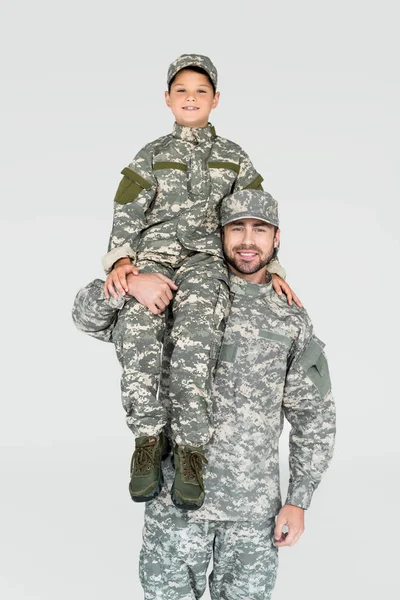 Leende Soldat Håller Son Militär Uniform Axel Isolerad Grå — Gratis stockfoto