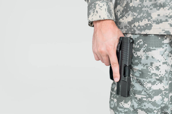 cropped shot of male soldier in military uniform holding gun isolated on grey