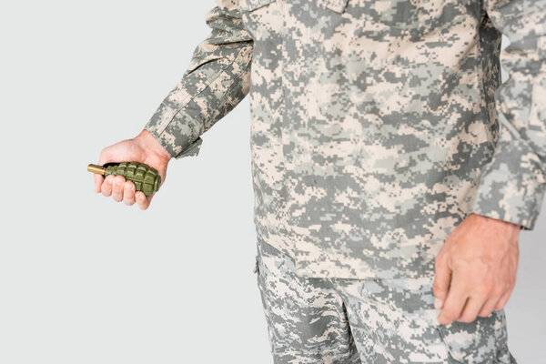 cropped shot of soldier holding grenade in hand isolated on grey
