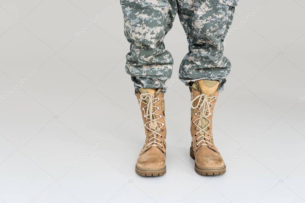 cropped shot of soldier in military uniform and boots isolated on grey