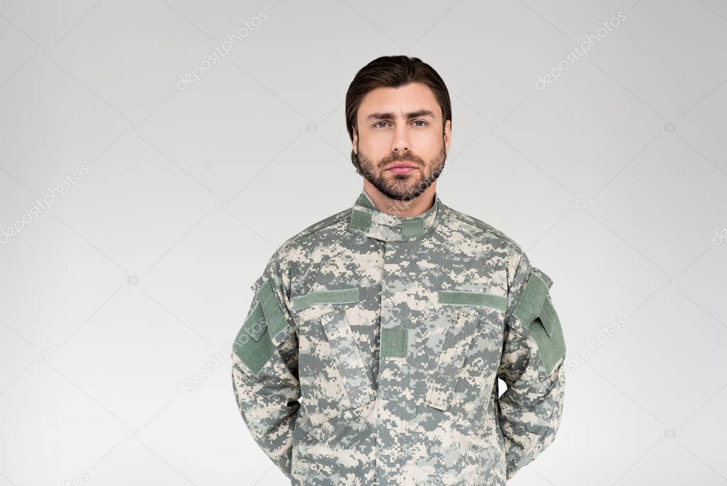 portrait of confident bearded soldier in military uniform on grey backdrop