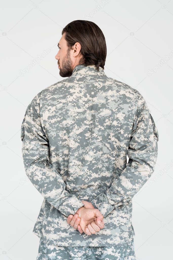 back view of male soldier in camouflage clothing isolated on grey
