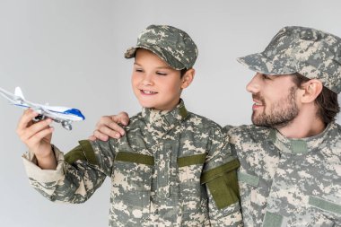 Baba ve oğul askeri üniforma gri izole oyuncak uçak ile portresi
