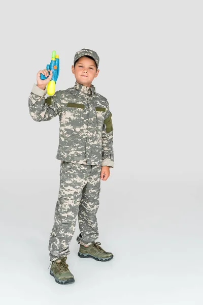 Little Boy Military Uniform Holding Toy Water Gun Grey Background — Free Stock Photo