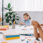 Enfoque selectivo de niños multirraciales con plastilina en las mesas en el aula