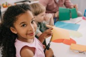 Selektivní fokus mnohonárodnostní Preschoolers řezání barevné papíry s nůžkami v učebně 