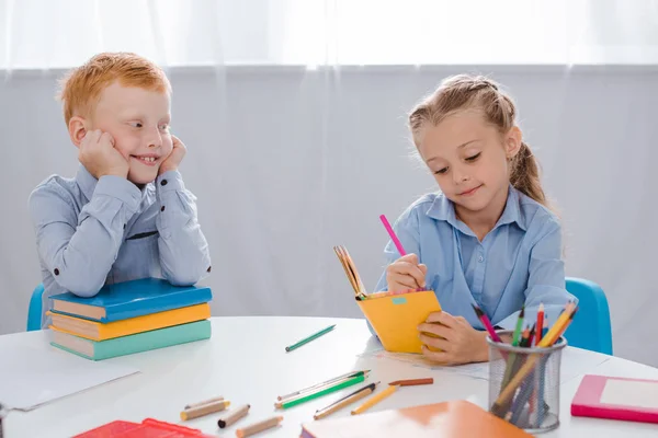 Retrato Niño Sonriente Pelo Rojo Mirando Compañero Clase Escribiendo Cuaderno — Foto de stock gratuita