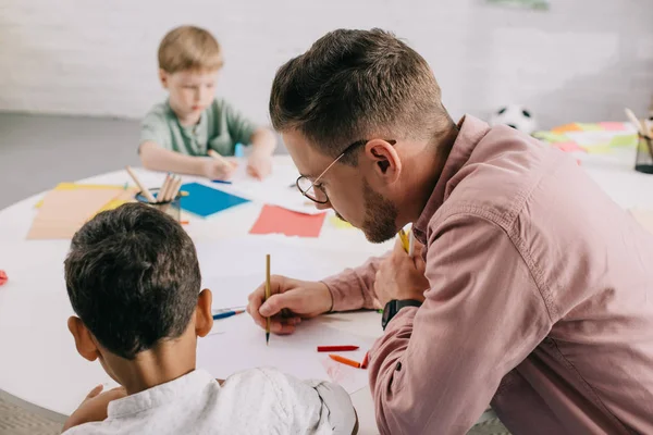 Selective Focus Teacher Multiracial Boys Drawing Pictures Colorful Pencils Table — Stock Photo, Image