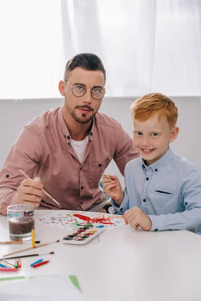 Portrait Teacher Little Boy Paint Brushes Sitting Table Classroom — Stock Photo, Image