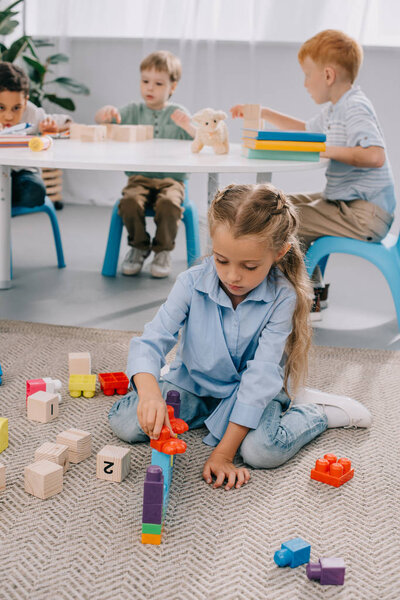 selective focus of multiracial preschoolers playing with blocks in classroom