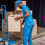 Αφρικανική αμερικανική courier βάζοντας κουτιά στο καλάθι