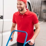 Smiling delivery man with cardboard box on delivery cart