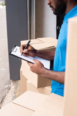 cropped image of african american delivery man writing something to clipboard  clipart