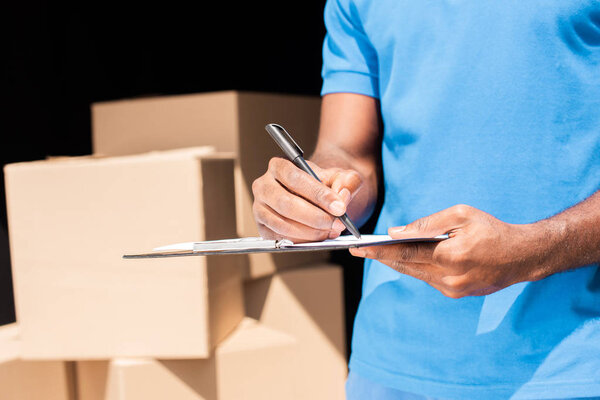 cropped image of african american delivery man writing something to clipboard 