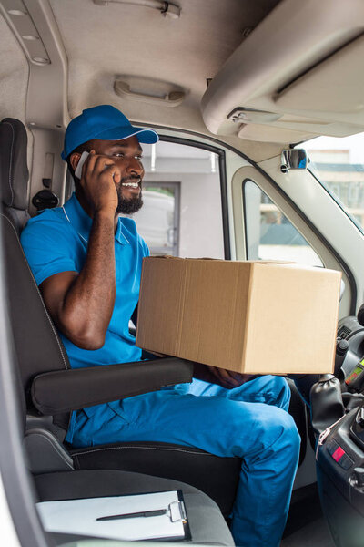 african american delivery man talking by smartphone in van