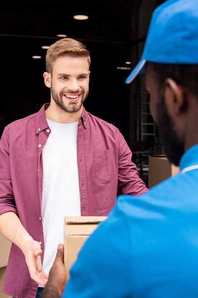 african american courier giving delivery box to smiling customer