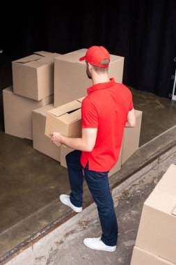 high angel view of young delivery man in red uniform discharging cargo clipart