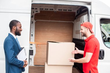 caucasian delivery man showing cargo to african american client clipart