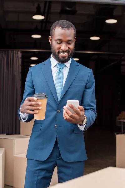 コーヒーをスマート フォンと笑顔のアフリカ系アメリカ人実業家の肖像画  — 無料ストックフォト