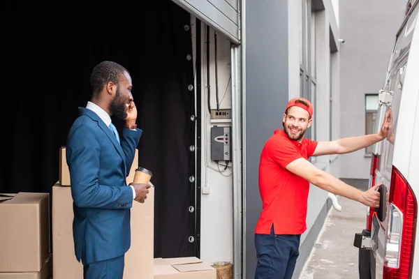 African American Businessman Coffee Controlling Caucasian Delivery Man While Talking — Stock Photo, Image