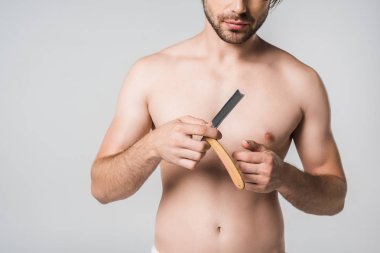 partial view of shirtless man with straight razor in hands isolated on grey clipart