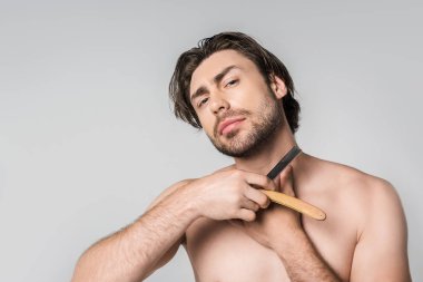 portrait of shirtless man with straight razor in hands isolated on grey clipart